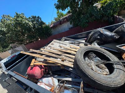 The 777 Junk Removal trailer loaded with lumber, scrap metal, a tire and bagged debris